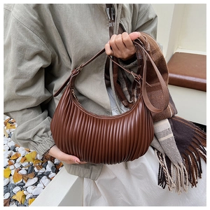 Gros plan détaillé sur la texture plissée marron en cuir PU d'un sac demi-lune