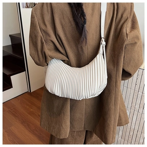 Détail du sac demi-lune plissé crème sur mannequin montrant la texture du cuir souple