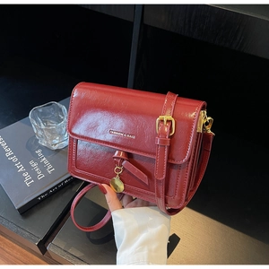 Detail of red wax leather crossbody bag with metal buckle and fashion lettering decoration