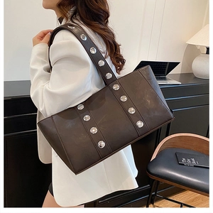 Détail d'un sac à bandoulière marron foncé avec grands rivets argentés et texture cuir