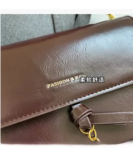Macro detail of dark brown faux leather bag with gold FASHION & BAG lettering and chain