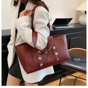 Detail of burgundy leather tote bag with oversized silver studs and polished finish