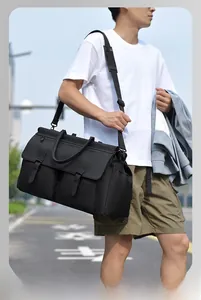 Outdoor shot of a large black travel bag with dual handles and padded shoulder strap