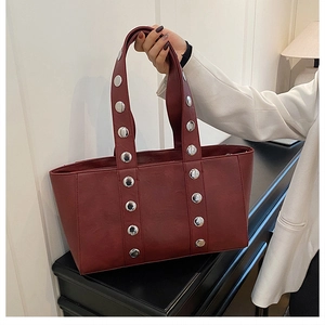 Macro detail of wine red tote bag featuring polished silver rivets and leather texture