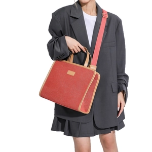 Red canvas crossbody bag with brown leather trim styled on a grey oversized blazer