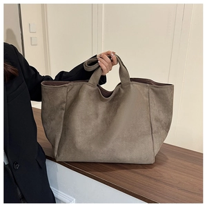 Detail view of large brown faux suede tote bag with wide handles and shoulder strap
