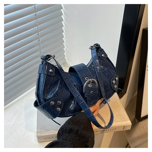 Détail du sac bleu foncé à motif crocodile avec clous argentés et finitions métalliques