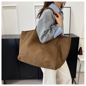 Brown suede tote bag shown on model with spacious design for daily commute