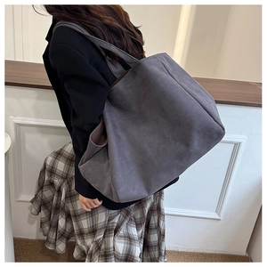Dark grey matte faux suede tote bag with wide shoulder strap shown on a model