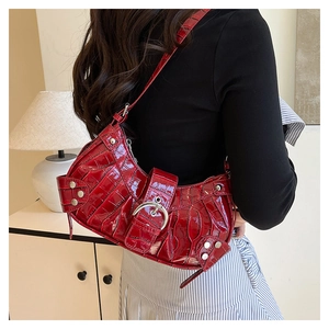 Détail du sac rouge à motif crocodile avec clous argentés et forme croissant Y2K
