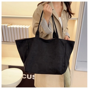 Detail of a large black suede tote bag with minimalist shoulder straps and matte finish