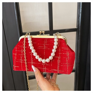 Macro shot of red velvet shell bag featuring gold grid pattern and pearl top handle
