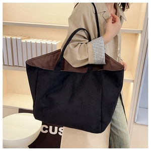 Spacious black matte tote bag shown on shoulder, highlighting large capacity and sleek design