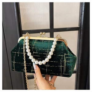Detail of dark green velvet shell bag with gold embroidery and large pearl handle