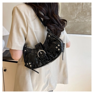 Détail du sac à bandoulière noir à motif crocodile avec clous argentés porté par un mannequin