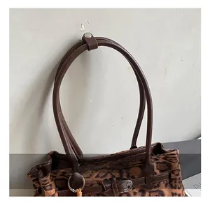 Detail showing leopard print texture with brown leather handle and silver metal rings