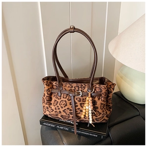 Detail of leopard print suede shoulder bag with brown leather strap and beaded pendant