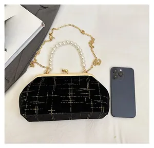 Detail showing elegant black velvet shell bag with pearl handle and golden chain strap