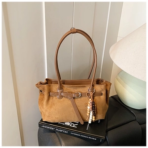 Detailed macro view of brown suede dumpling bag with leather strap and wood bead ornament