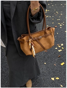 Detail of caramel suede bag with fringe charm and autumn street photography style