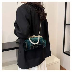 Detail of dark green velvet quilted shell bag with pearl handle and gold chain strap