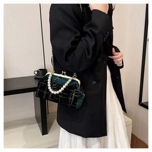 Detail of dark green velvet shell bag with gold lattice and pearl handle strap