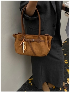 Autumn style street shot of a brown suede dumpling bag with elegant beaded pendant detail