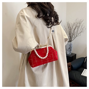 Detail of red velvet bag with pearl handle and gold chain on beige coat