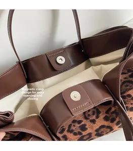 Detail of magnetic silver closure on leopard print suede tote bag with beige lining