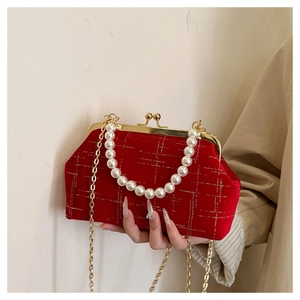 Detail of red velvet bag with pearl top handle and golden chain strap for evening events