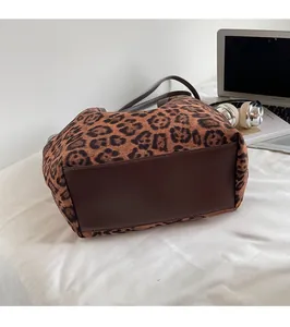 Close-up of leopard print tote bag with reinforced brown leather base on a desk