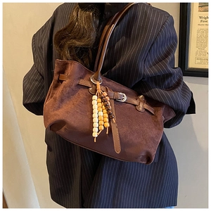 Detail of dark brown faux suede tote bag with wooden bead tassel and slim leather strap