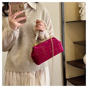 Detail of rose red velvet handbag with gold lattice patterns and large pearl handle