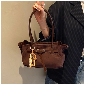 Detail of brown faux suede tote bag with ethnic wooden bead charm and long straps