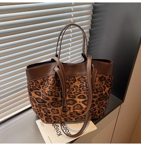 Detail of leopard print tote bag with brown leather handles and sturdy suede texture