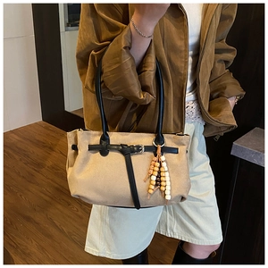 Detail of khaki frosted suede bag featuring black leather strap and beaded charm accent