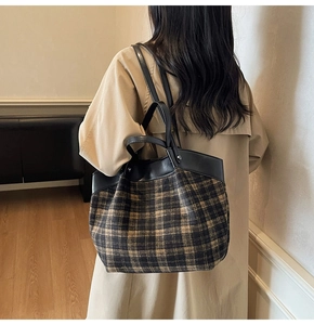 Detail of checkered tote bag with leather straps worn with a beige trench coat