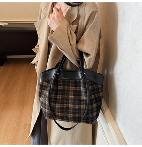 Detail of vintage plaid tote bag featuring black leather trim and woven fabric texture