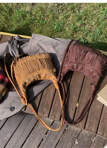 Detail of bohemian suede shoulder bags with fringe tassels and star-shaped metal rivets