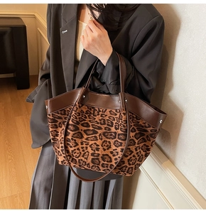 Detailed view of leopard print tote bag with brown leather handles worn by a model