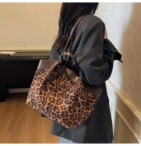 Detail of leopard print tote bag with brown leather trim shown on model's shoulder