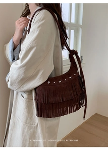 Detail of dark brown hobo bag featuring retro tassels and silver star rivets