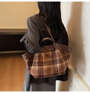 Detail of vintage brown plaid tote bag with leather trim and silver rivets on shoulder