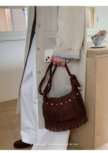 Detail of dark brown suede crescent bag with long fringes and silver star studs