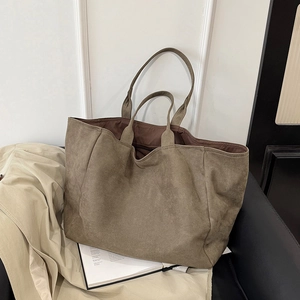 Large olive green tote bag in faux suede on a chair, minimalist style for daily commute