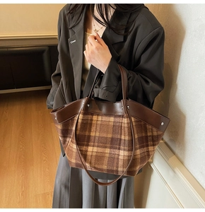Detail of vintage brown plaid tote bag featuring leather handles and metal rivet accents