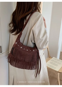 Detail view of brown suede crossbody bag featuring silver star studs and long fringe tassels
