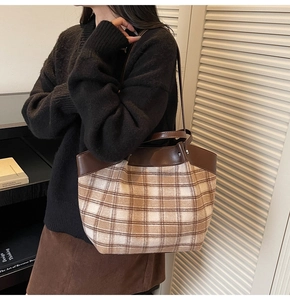 Detail of vintage plaid tote bag with brown leather trim and handles for daily commute