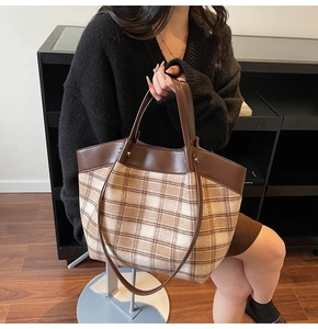 Detail of leather stitching and brown plaid pattern on a large capacity tote bag