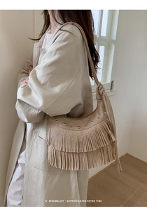 Close-up of retro beige suede shoulder bag with silver star studs and bohemian tassels